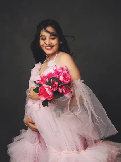 The gentle breeze in her hair, the soft pink of the dress, the joyful smile. This is a perfect capture of the happiness of expecting.