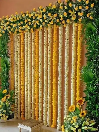 A beautiful floral wall made of alternating yellow and white flower strings. This simple yet elegant backdrop is perfect for Haldi, Mehendi, or any traditional ceremony.