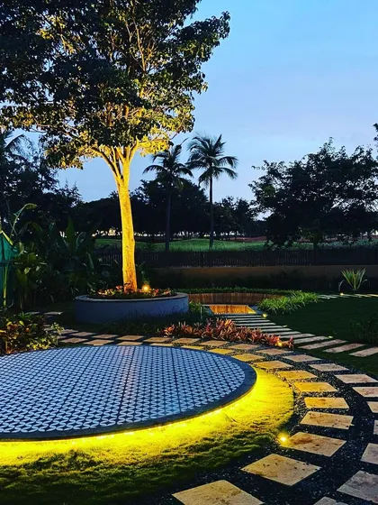 The circular patio, lit from below, appears to float in the lawn, creating a stunning visual feature.