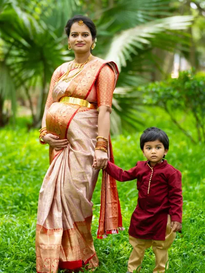 The sweet anticipation of a new arrival is a precious family moment. We specialize in maternity shoots that include older siblings, capturing the unique bond and excitement as your family grows. This outdoor portrait in a beautiful silk saree shows a quiet, loving moment between a mother and her son.
