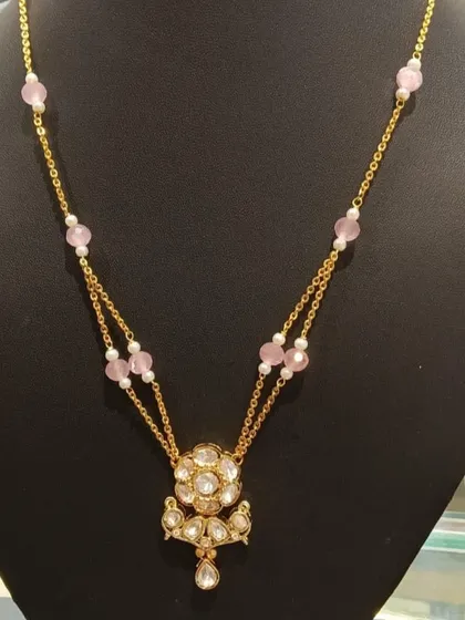 A delicate double-strand necklace with a floral Kundan pendant and soft pink beads. This is a perfect piece for a thoughtful gift or for adding a touch of elegance to your everyday style.