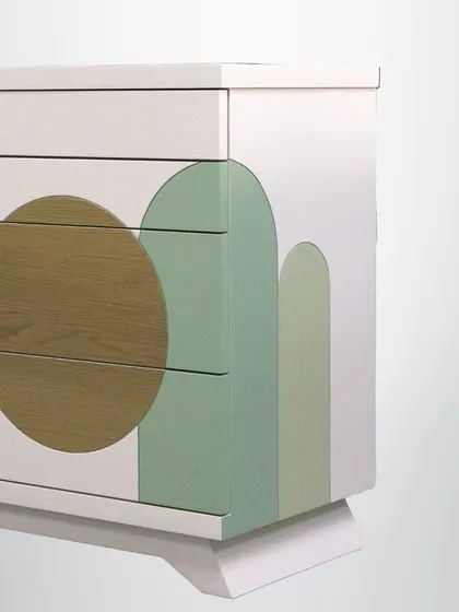 A detail of the geometric storage unit, showing the precise inlay work and the seamless integration of different materials and colors. The drawers provide practical storage, hidden behind a beautiful facade.