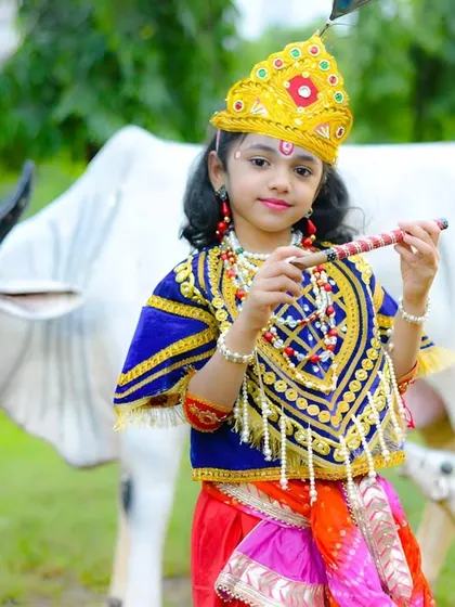 A wonderful themed portrait for Janmashtami, with little Krishna posing with a flute next to a statue of a cow.