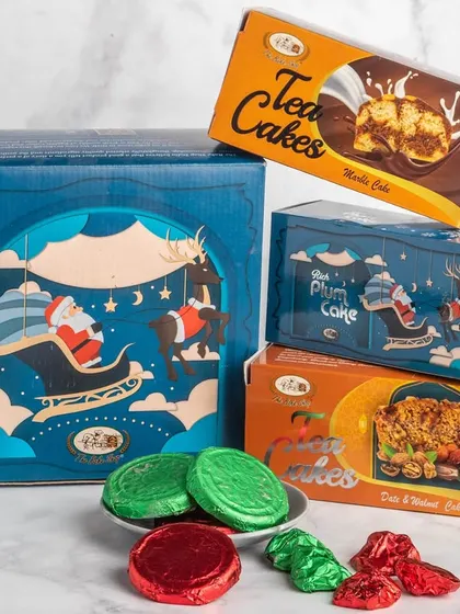 Our Cozy Christmas Comfort Hamper is perfect for a festive night in. It features a rich plum cake, a marble tea cake, a date and walnut tea cake, chocolate biscuits, and assorted chocolate rocks.