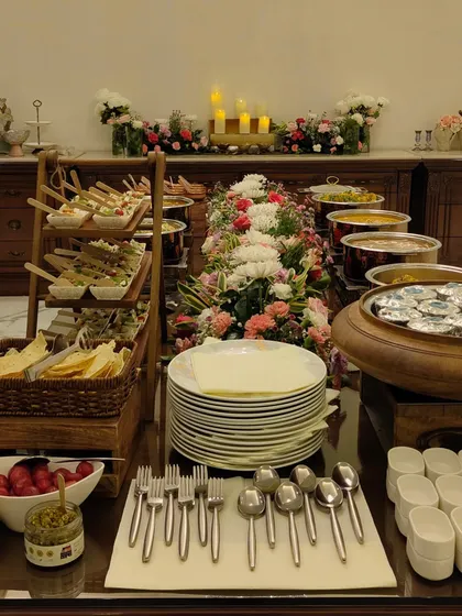 A beautiful buffet spread decorated with an abundance of fresh flowers. This setup includes tiered stands for appetizers and a variety of main courses in elegant serving dishes.