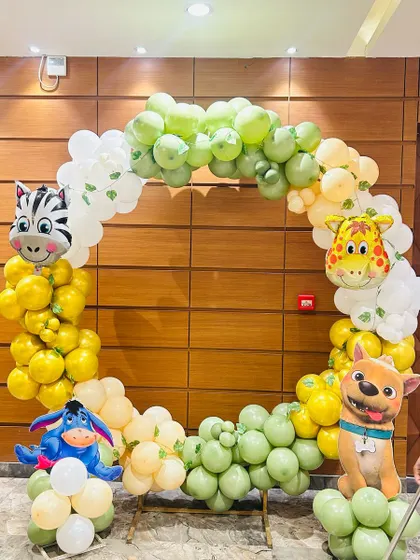 A circular balloon arch for an animal-themed party. The arch is decorated with cute animal character balloons like a zebra, giraffe, and Eeyore.