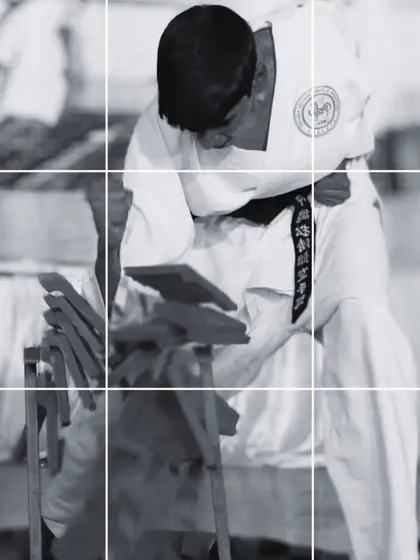 A focused moment during a Tameshiwari demonstration. The student's form shows the concentration required just before impact to break through the boards.