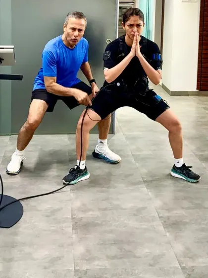 My hands on guidance ensures the client maintains correct form during a squat, which is crucial for effective and safe training.