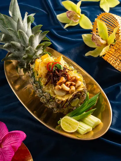 Another angle of the pineapple fried rice from Nara Thai, set against a rich blue velvet background that makes the gold serving dish pop.