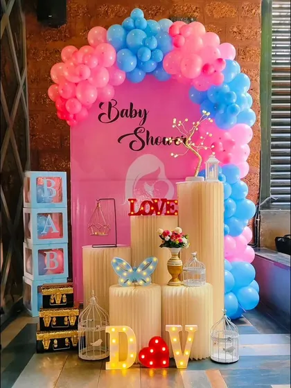 A popular "gender reveal" style baby shower decoration. The pink and blue theme is carried through the balloon arch, backdrop, and props, creating a fun and exciting atmosphere.