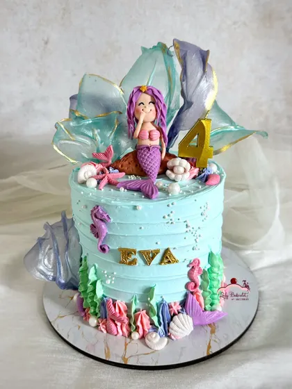 A fintastic mermaid cake with a hand-sculpted mermaid, translucent rice paper sails, and lots of shimmering details.