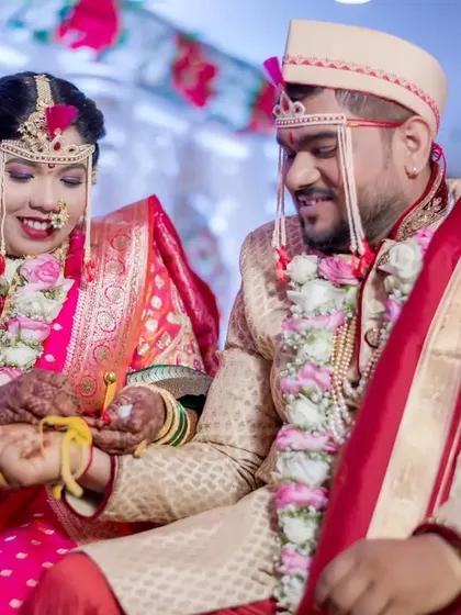 The couple participates in a traditional ritual involving a sacred thread, their focus and smiles making it a beautiful moment.