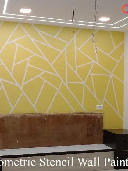 A geometric stencil design in progress behind a bed. The intersecting lines on a bright yellow wall create a vibrant and modern headboard feature that energizes the entire bedroom.