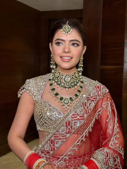 Crafting bridal perfection, one flawless detail at a time. Here’s Ritika, flaunting that bridal radiance in her red Manish Malhotra lehenga with a soft, glowing makeup look.
