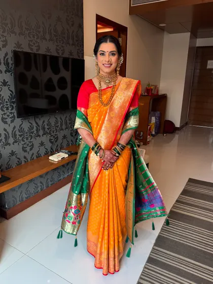 A full-length view of a stunning Maharashtrian bride. Her hair is elegantly styled to support her dupatta, and the makeup is designed to be flawless both in person and in photographs.