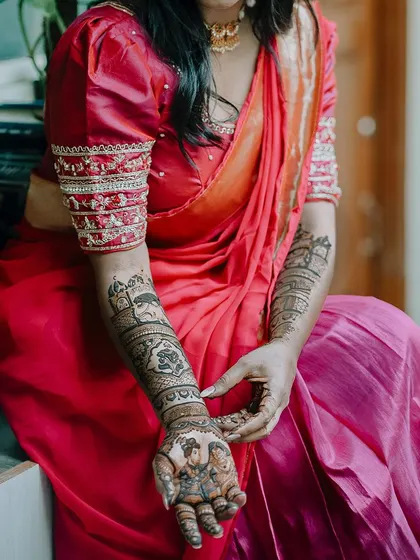 A full view of a stunning bridal mehendi with storytelling elements. The design includes portraits and architectural motifs, covering the arms in detailed artistry.