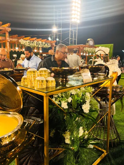 A guest helps himself to a serving of traditional Mutton Mandi from an elegant brass chafing dish.