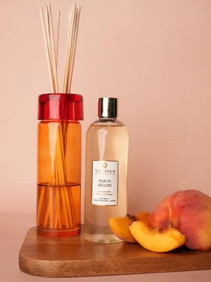 The sweet and juicy scent of Peach Bellini, captured in our reed diffuser. Paired with fresh peaches, this image showcases the natural inspiration behind our vibrant fragrances.