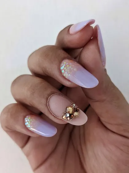 A delicate and dreamy look with lavender ombre, glitter, and a stunning crystal accent nail. This is a perfect example of a soft yet glamorous design.
