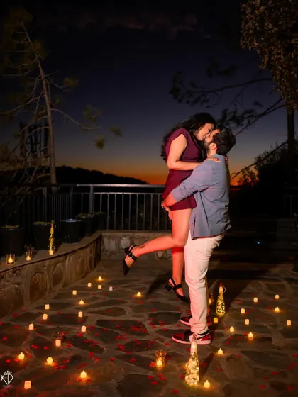 An intimate moment captured on a terrace surrounded by candles, with the twilight sky painting a perfect romantic backdrop. These carefully planned evening shoots create a magical atmosphere.