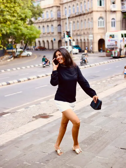 A smiling, candid shot while pretending to be on the phone, perfect for creating a natural, lifestyle narrative for a brand.