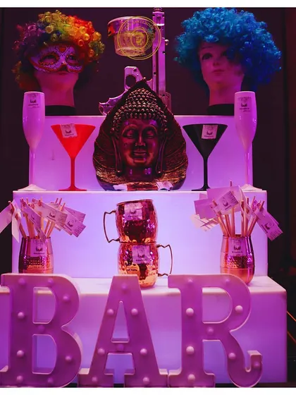 A quirky and fun bar display. We use elements like mannequin heads with colorful wigs, illuminated signs, and unique glassware to create a playful and memorable setup.