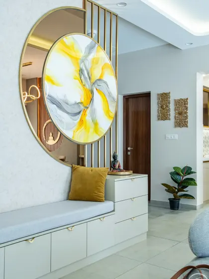 A custom-designed entryway bench provides both seating and storage. The space is defined by a stunning circular art piece set against a metal rod partition, creating a beautiful and welcoming first impression.