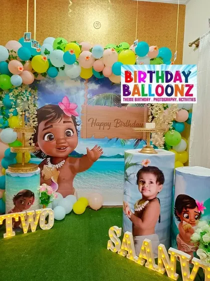 An adventurous Moana theme, perfect for a tropical birthday celebration. This decor features a large Baby Moana cutout, a beach scene backdrop, and pedestals customized with photos of the birthday girl dressed as Moana.