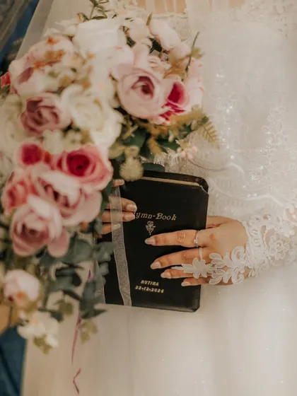 A detailed shot of the bride holding her hymn book and bouquet, capturing the personal and religious elements of the day.