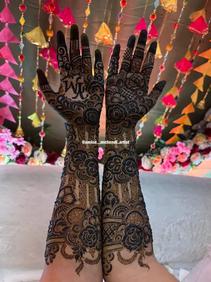 A stunning full-arm design with the initials 'YM' prominently featured on one palm, set against a festive, decorative background.