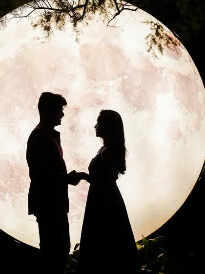 A classic and timeless silhouette of a couple against a giant moon prop.