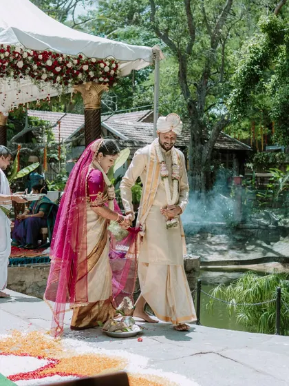 The couple walking together during their outdoor wedding ceremony, with sacred smoke in the background.