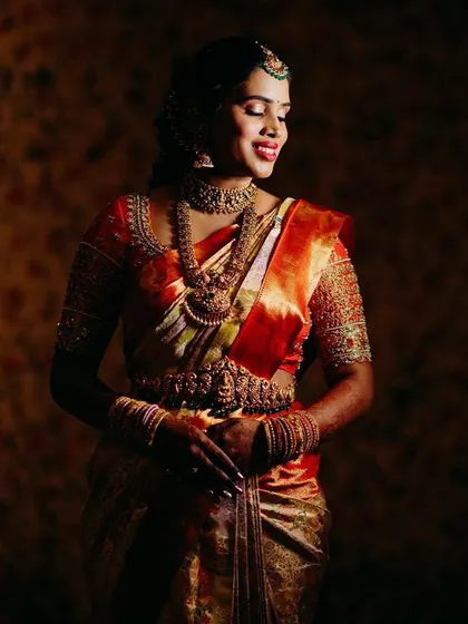 An artfully lit shot of the bride in her orange Kanjeevaram, creating a dramatic and elegant portrait.