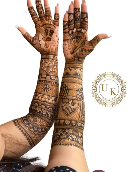 A full-coverage bridal design shown from a unique angle. The patterns are intricate and flow beautifully from the hands up the arms, showcasing a classic bridal style.