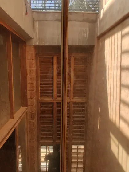 Looking down into a double-height space with wooden louvered windows during construction.
