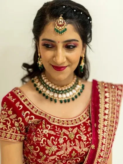 A close-up portrait of the bride's reception makeup. The pink eyeshadow, bold lip, and defined brows frame her face beautifully.
