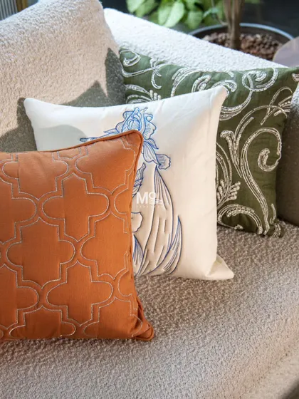 A trio of cushions in the colors of the Indian flag, celebrating Independence Day. The set includes a burnt orange with a geometric pattern, a white cushion with blue floral embroidery, and a green one with a classic scroll design.