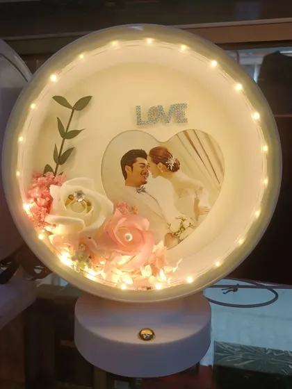 Our round 3D LED lamp offers a different style but with the same magical effect. It includes a photo, flowers, and a 'Love' sign, all illuminated by warm LED lights.