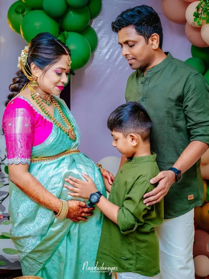A heartwarming family moment at a baby shower. The older brother gently places his hand on his mother's bump, excited to meet his new sibling.