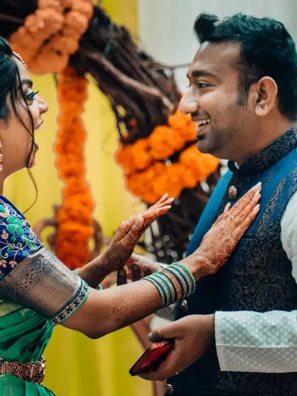 A candid moment of a bride playfully touching her groom's chest during their wedding celebration.