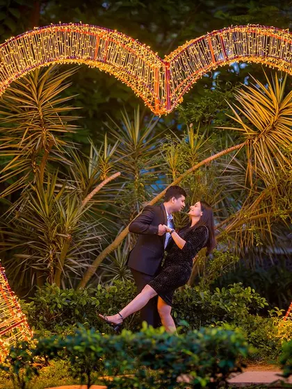 A dynamic and joyful pose inside the giant illuminated heart. The couple's dance-like posture adds a sense of fun and celebration to this classic romantic shot.