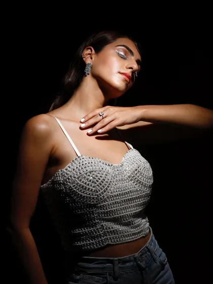 This image uses a single spotlight to create a dramatic, high-contrast effect. The model's pose and the focused light on the beaded top give the shot an intimate and artistic feel.
