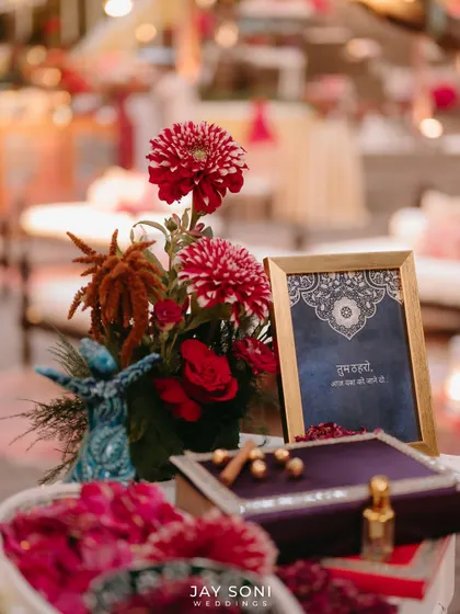 A tabletop vignette from the Mehfil-e-Mehendi, featuring a miniature whirling dervish, a floral arrangement, and an ornate box.