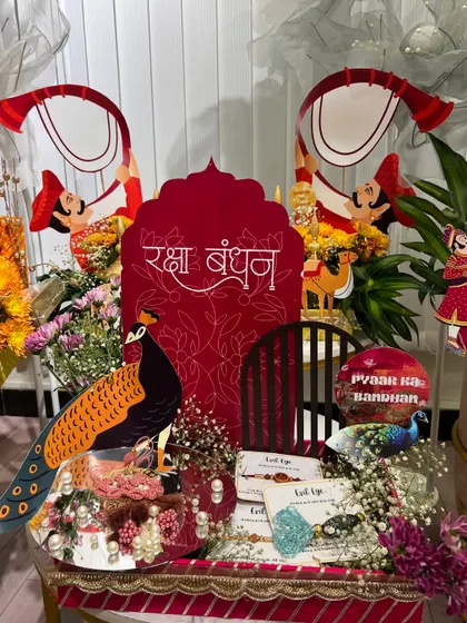 This Rakhi trousseau for a bride-to-be is a perfect example of our detailed work. The setup features a 'Raksha Bandhan' centerpiece, peacock motifs, and beautifully arranged Rakhis and gifts on a mirrored tray.