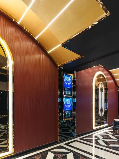 The arched entryways along the main corridor of INOX Jalosa are framed with glowing light, creating a rhythmic and visually engaging journey. The deep red walls and geometric flooring contribute to a cohesive and luxurious design language that runs throughout the megaplex.