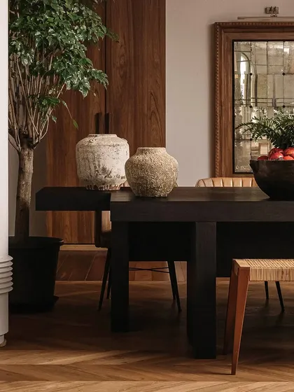 A detail shot of the meeting table, showcasing the contrast between the dark wood, rustic pottery, and an antique-finish mirror. These are the details that build a rich, layered narrative.