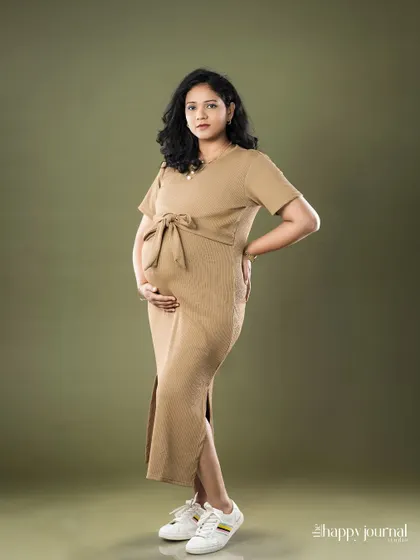A full-length portrait showing a modern maternity style. The simple dress and sneakers create a look that is both comfortable and chic.