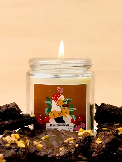 The rich, decadent scent of a fudge brownie candle is visualized by surrounding it with actual fudge brownies. This direct and delicious approach makes the fragrance almost tangible.