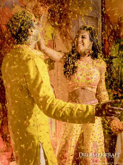 A playful moment as the couple is showered with flower petals during their Haldi, capturing the fun and joy of the ceremony.
