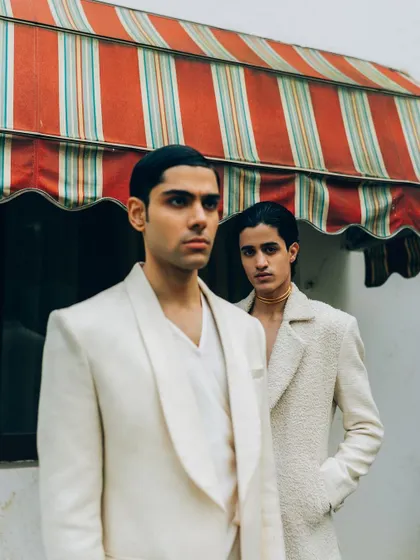 A menswear editorial for designer Sanchit Sharma. The composition uses architectural elements and clean lines to frame the subjects, creating a sophisticated and modern look.